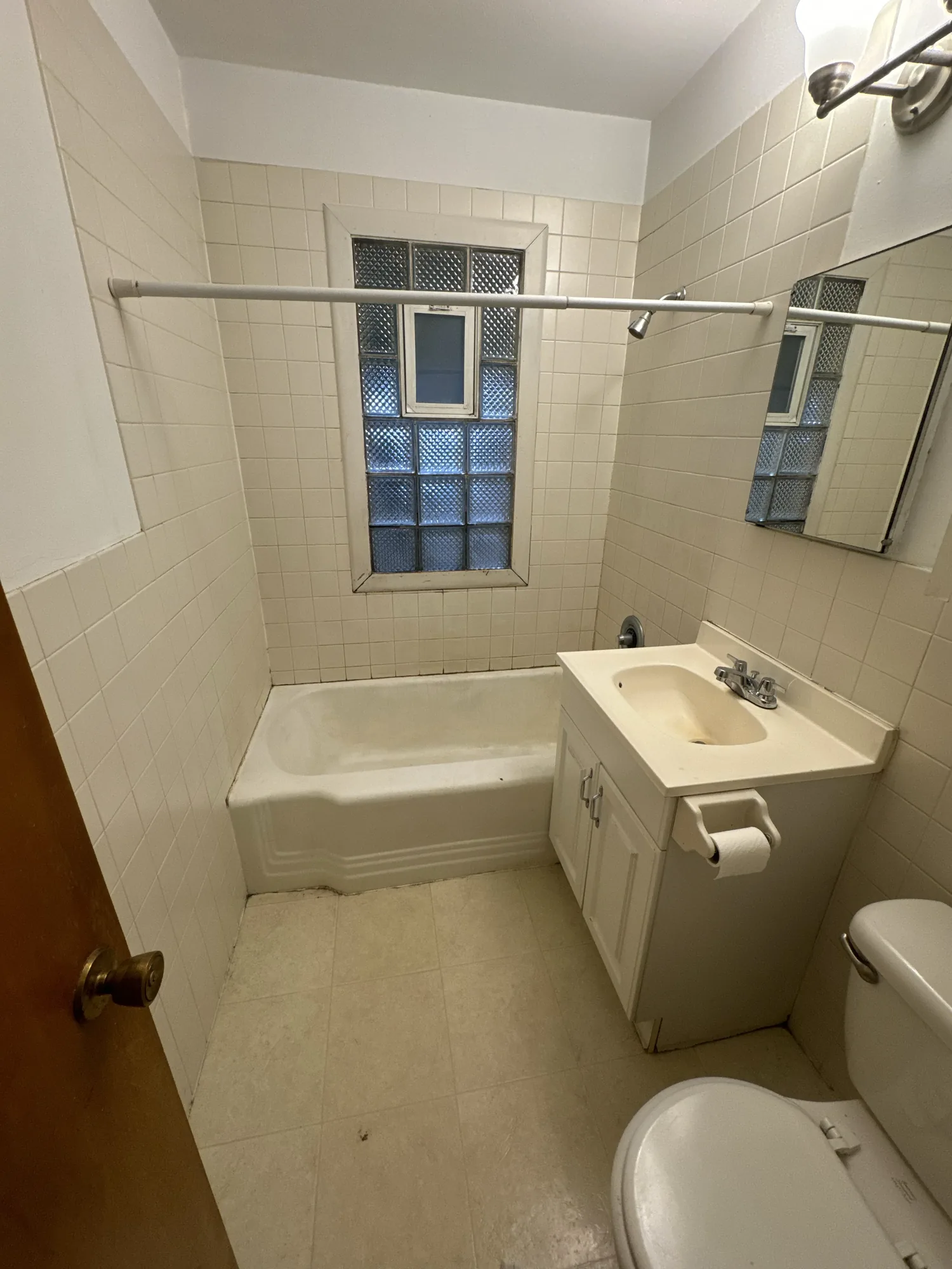 Original duplex bathroom before painting, with tiled walls and dated fixtures