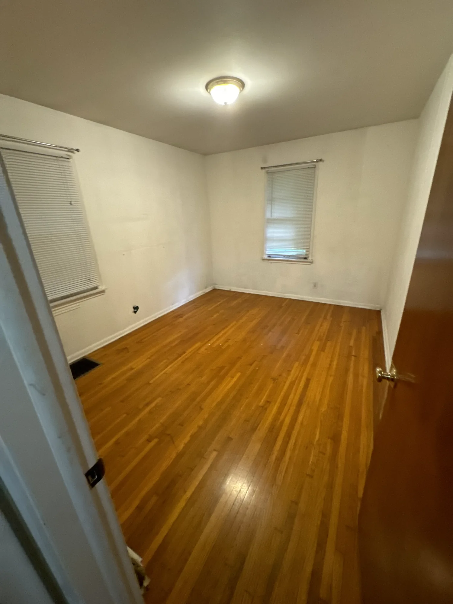Bedroom with wood paneling and worn paint before repainting in a Northeast Minneapolis duplex