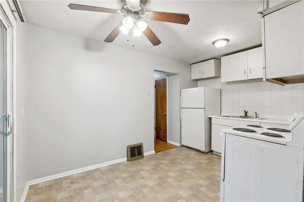 The same Northeast Minneapolis duplex kitchen after painting, with fresh light grey walls and the original cabinets and appliances kept in place