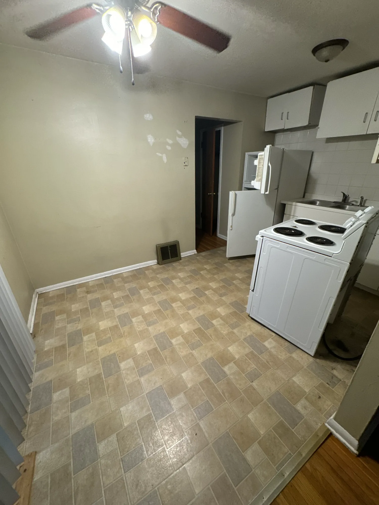 Dated kitchen in a Northeast Minneapolis duplex before painting, with beige walls and original white cabinets