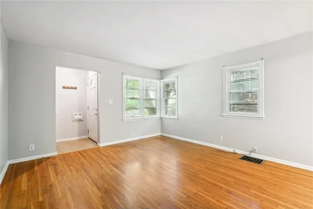 Bright repainted living room with clean white walls and refinished hardwood floors in a Northeast Minneapolis duplex
