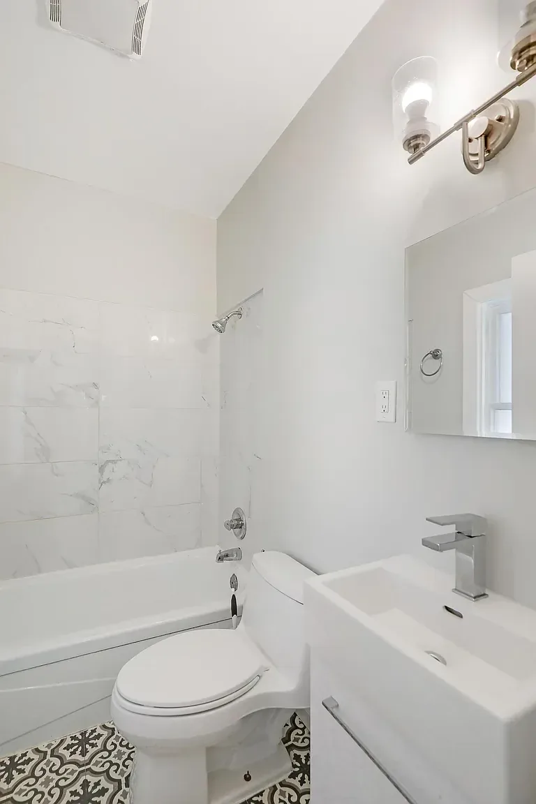 Bathroom after painting, with white walls and ceiling above updated tile
