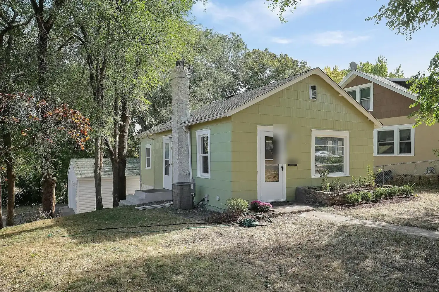 Side view of the repainted St. Louis Park bungalow showing green siding and fresh white window trim