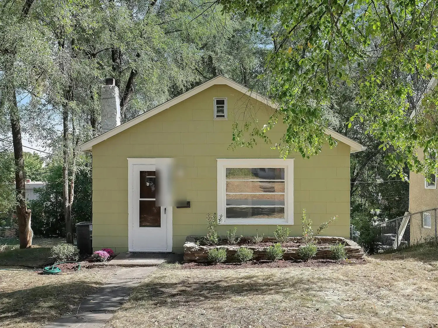 St. Louis Park bungalow repainted in soft yellow-green with white trim and a white front door