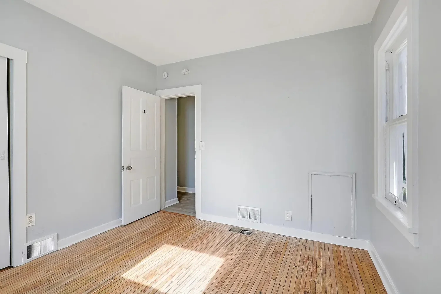 Second bedroom after painting, empty with light hardwood floors and grey walls